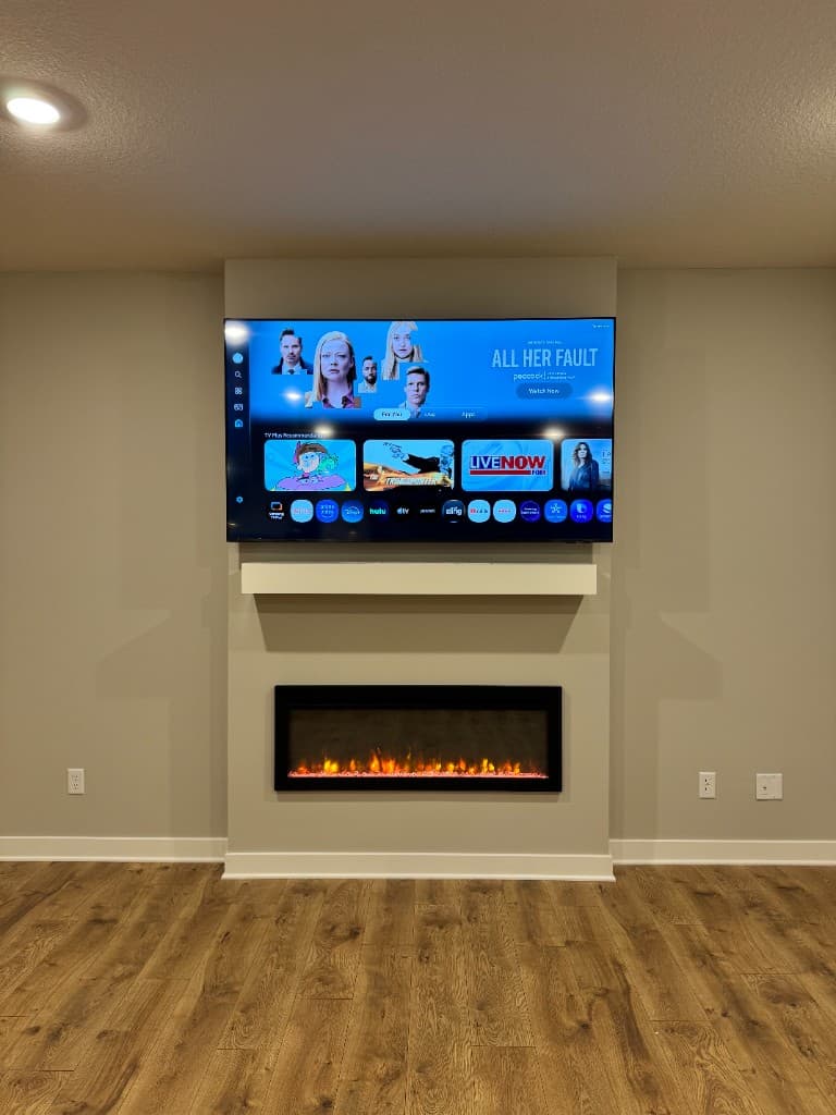 Large TV mounted above an electric fireplace with clean cable management