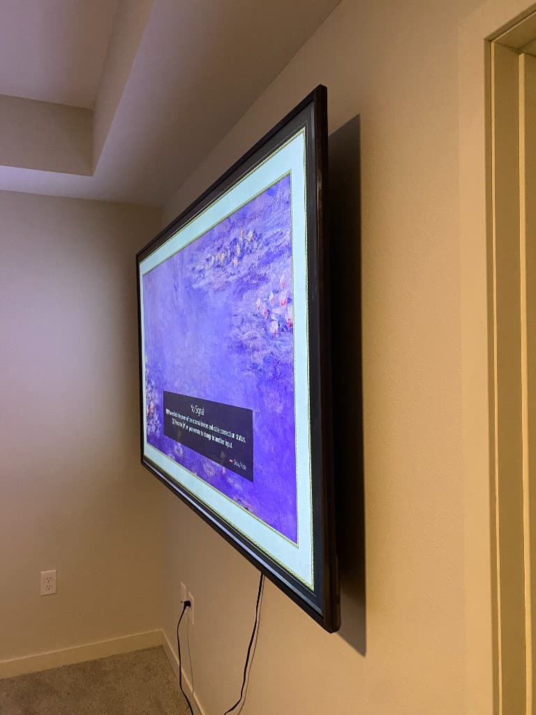 Samsung Frame TV mounted on wall displaying art in a decorative frame